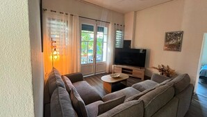 Un saló amb un sofà, televisió i un ventilador de sostre.