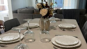 Taula de dinar preparada amb plats, gots i coberts, i un ram de flors al centre.