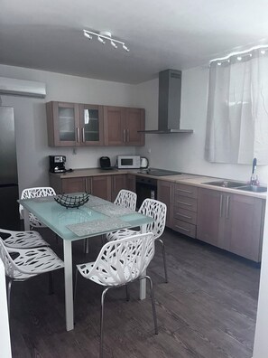 A compact kitchen with a dining area, including a table, chairs, and a microwave. - Fabulous 2-bedroom apartment with AC in Kalivia Thorikou (Kalivia Thorikou)