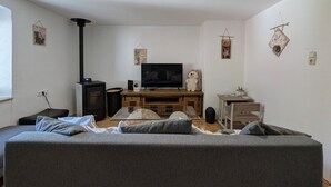 Un salon avec un canapé, un téléviseur, un meuble en bois et une petite table.