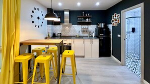 Eine moderne Küche mit Kochinsel, Barhocker, einem schwarzen Kühlschrank und einer gefliesten Spritzschutzwand.