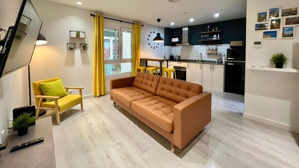 Ein modernes Wohnzimmer mit einer Couch, einem Essbereich und einer Küche mit Schränken und Geräten.
