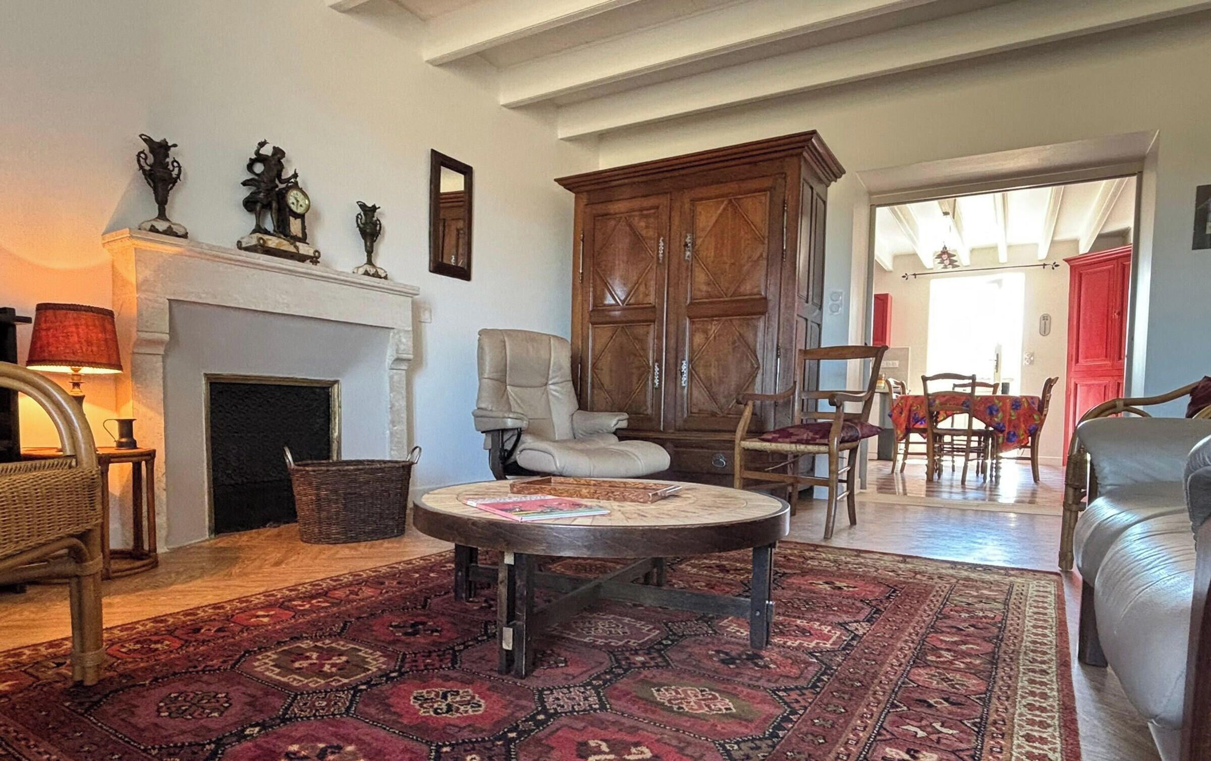 A living room with a fireplace, a round coffee table, and a large wooden cabinet.