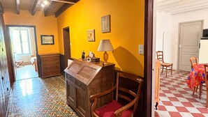 Ein Zimmer mit einem Holztisch, einem Stuhl, einer Lampe, einem Bett und einem gemusterten Boden.