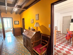 Um quarto com escrivaninha de madeira, uma cadeira, abajur, cama e piso estampado.