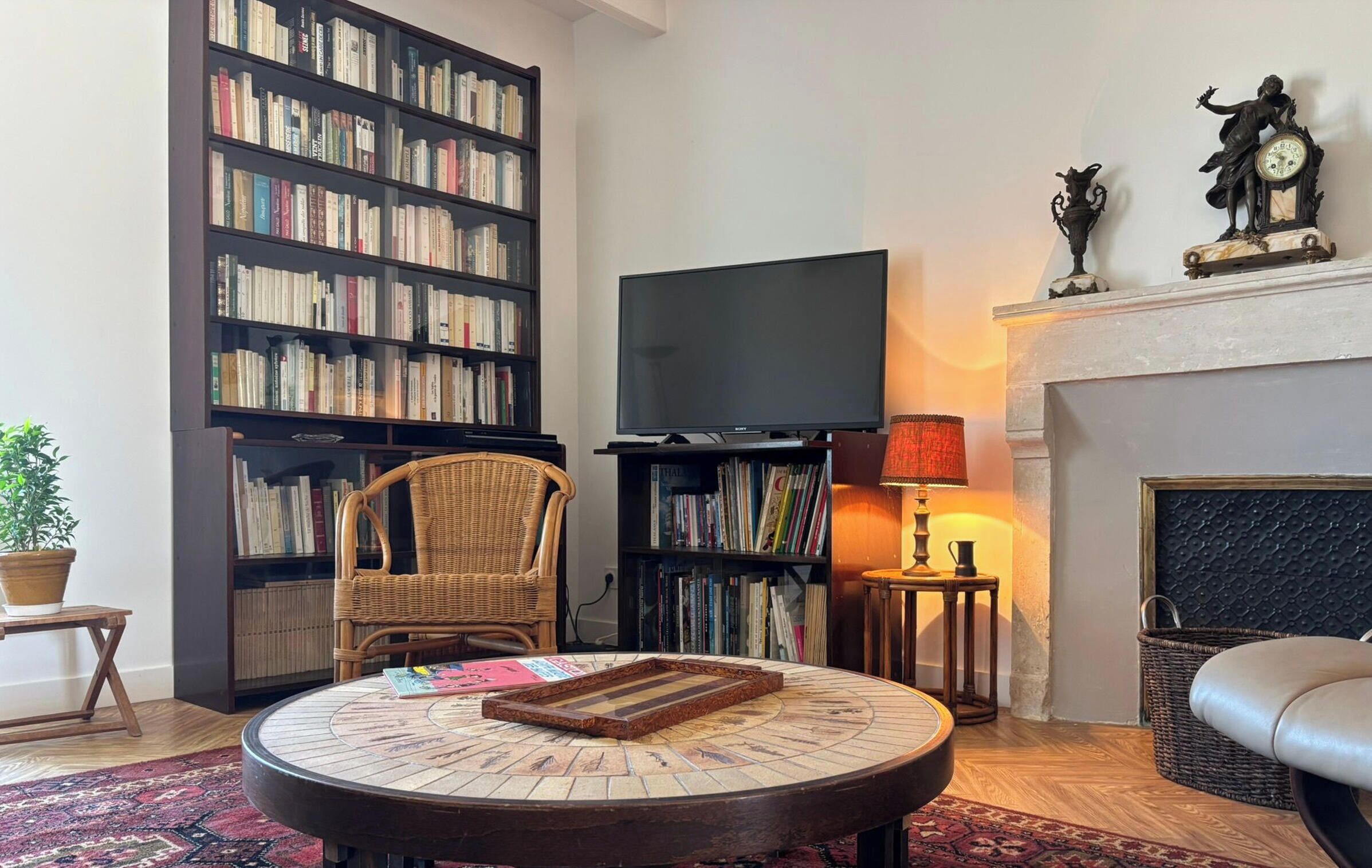 A living room with a bookshelf, a flat-screen TV, a fireplace, and a round coffee table.