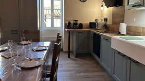 Een keuken met een eettafel gedekt voor vier personen, een koffiezetapparaat, een magnetron en een klok aan de muur.