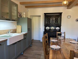 Una cocina con una mesa de madera dispuesta para comer, armarios y un aparador decorativo con platos.