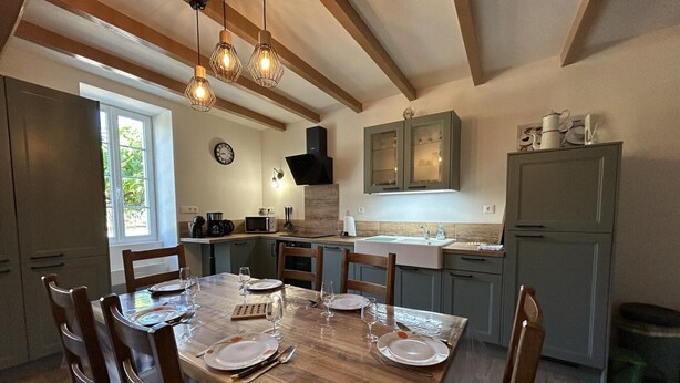 Een eetgedeelte met een houten tafel gedekt voor vier personen, een keuken met moderne apparatuur, en een raam dat natuurlijk licht binnenlaat.