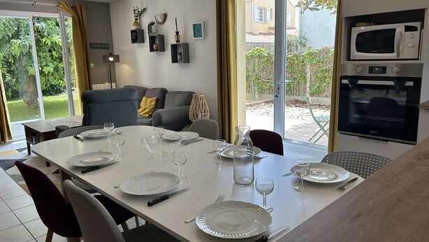En matplats med ett bord för fyra personer, en soffa, ett kök med mikrovågsugn och ugn samt en skjutdörr i glas som leder ut till uteplatsen.