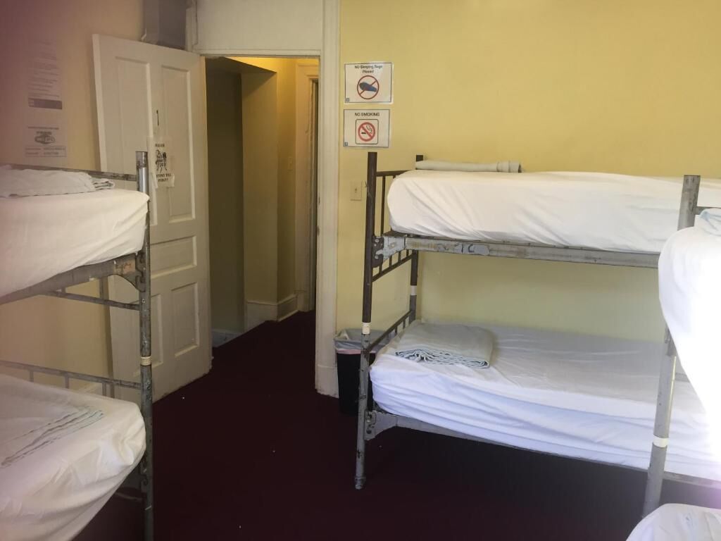 Une chambre avec des lits superposés, une porte et un panneau indiquant qu'il est interdit de fumer.