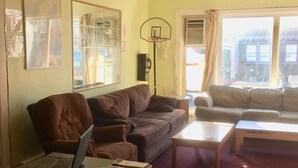 Een woonkamer met een bank, een salontafel, een laptop en een basketbalring.