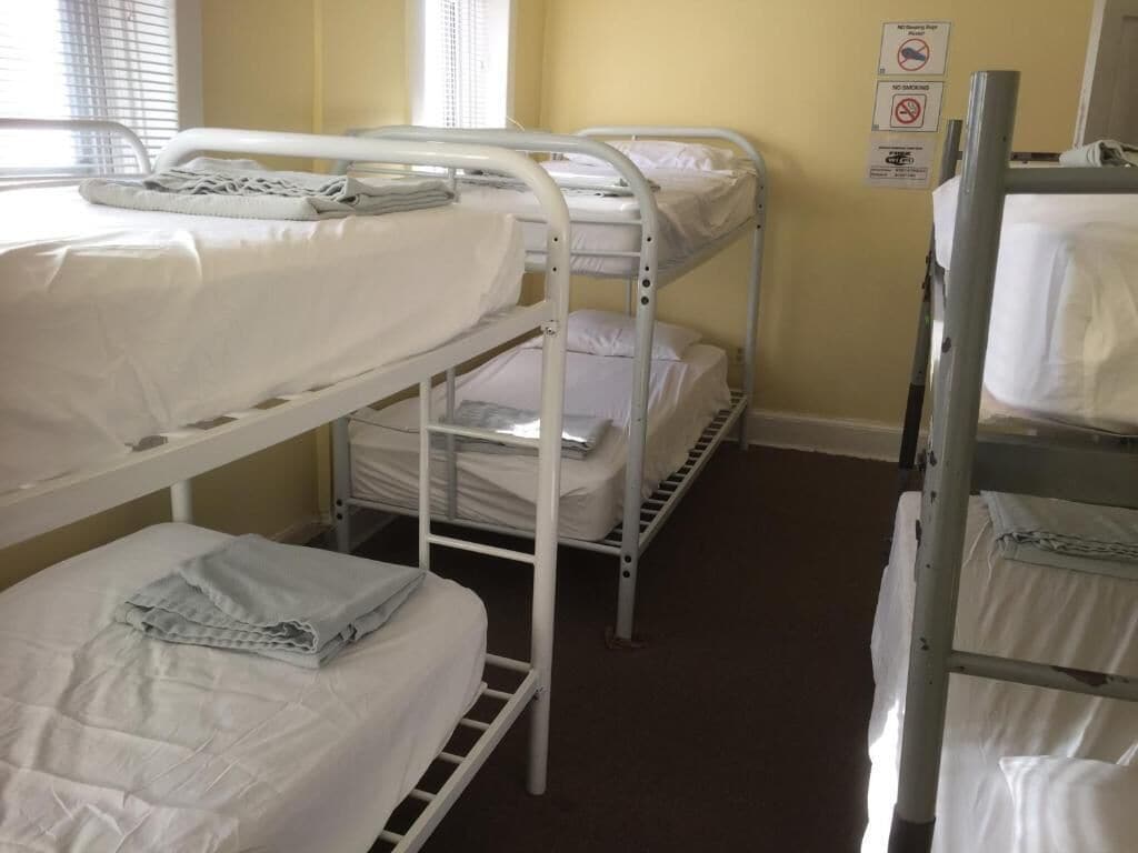 A bunk room with three bunk beds, each with white bedding.