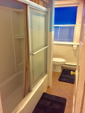 A narrow bathroom with a shower, toilet, and a window. - Washington Capital Hostel (Washington)