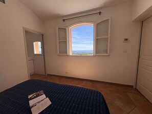 A bedroom with a bed, a window with open shutters, a radiator, and a door. - Apartment with AC, sea view - 6 guests (Saint-Cyr-sur-Mer)
