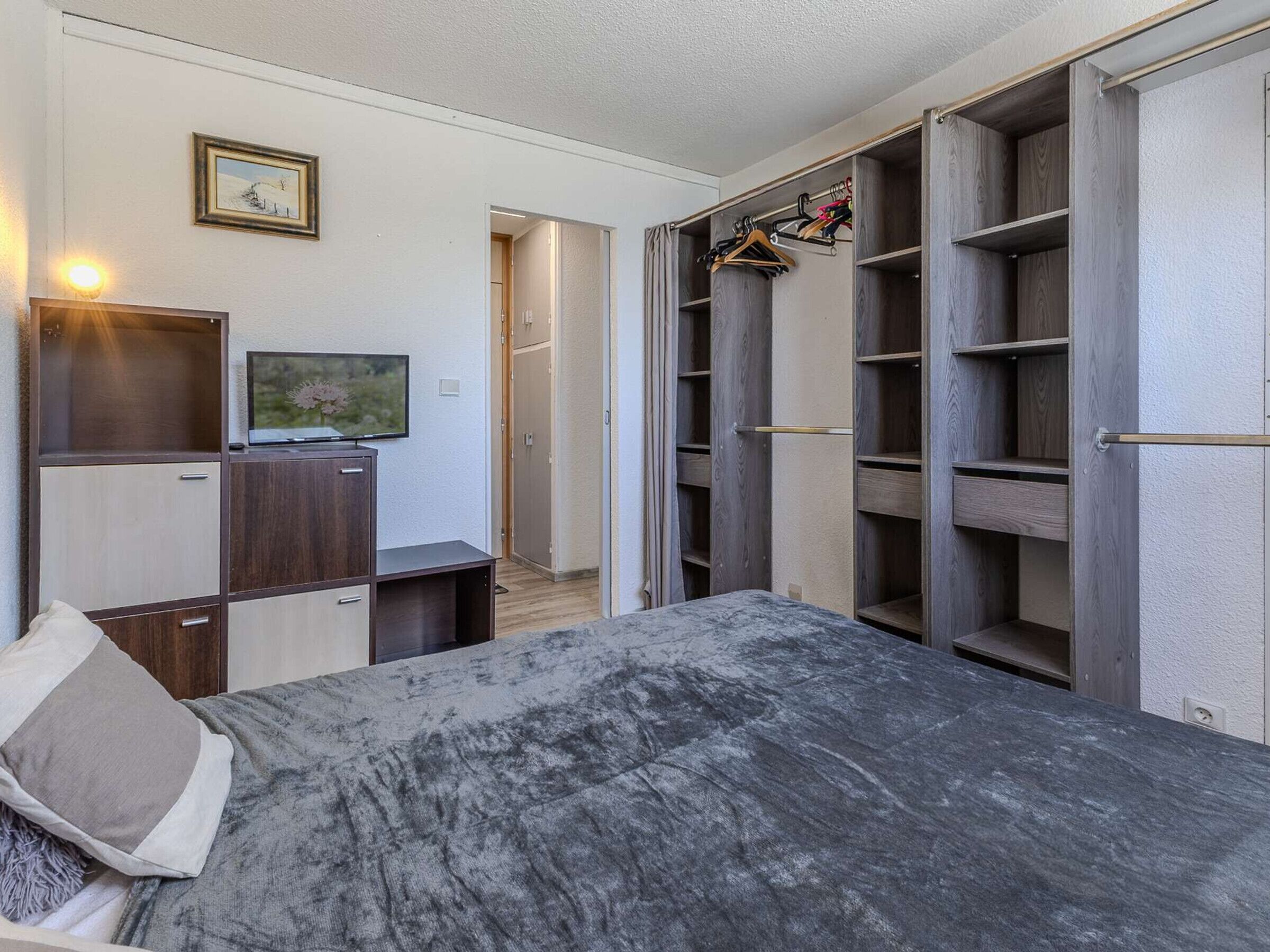Een slaapkamer met een bed, een televisie, een kledingkast en een inloopkast.