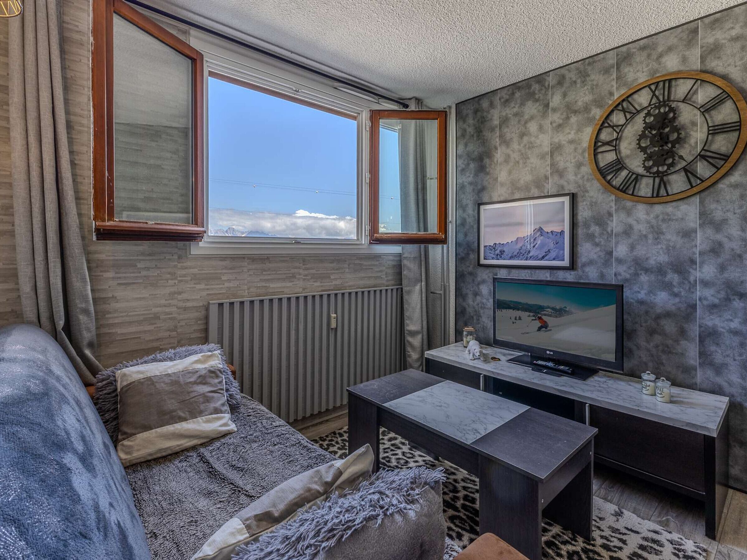 A modern living room with a sofa, a coffee table, a TV, and a wall clock.