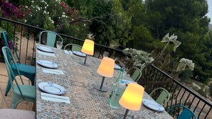 An outdoor dining area with a patterned tablecloth, white plates, and green chairs. - Family home in a small but quiet tourist village (VC)
