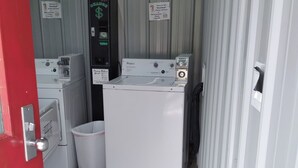 Uma lavanderia com máquina de lavar, secadora e máquina de lavar à moeda.
