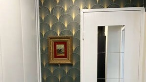 Une porte blanche avec un miroir, un tableau encadré accroché au mur et un papier peint à motifs.