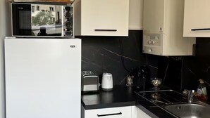 Une cuisine compacte équipée d’un réfrigérateur, d’un four à micro-ondes, d’un grille-pain et d’un évier.