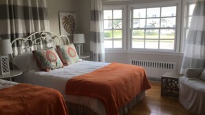 A bedroom with a bed, two bedside tables, a window with curtains, a radiator, and a view of the outside. - Ocean Block.  Amazing 5-bedroom house with AC in charming Spring Lake! (Spring Lake)