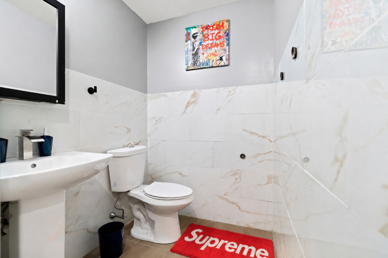 A bathroom with a white sink, toilet, and marble walls.