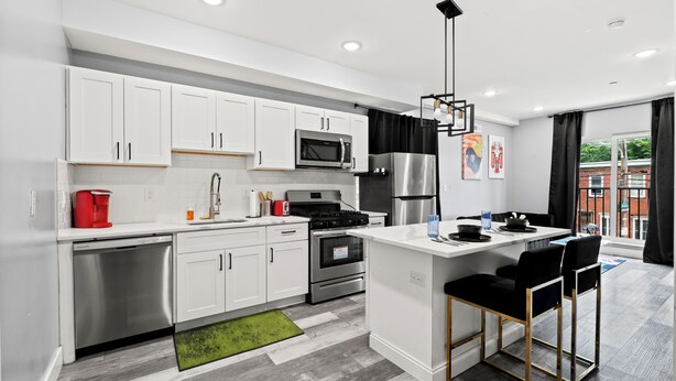 A modern kitchen with white cabinets, stainless steel appliances, and a central island with bar stools. - Spacious 2-bedroom apartment in fabulous Philadelphia with AC (Philadelphia)