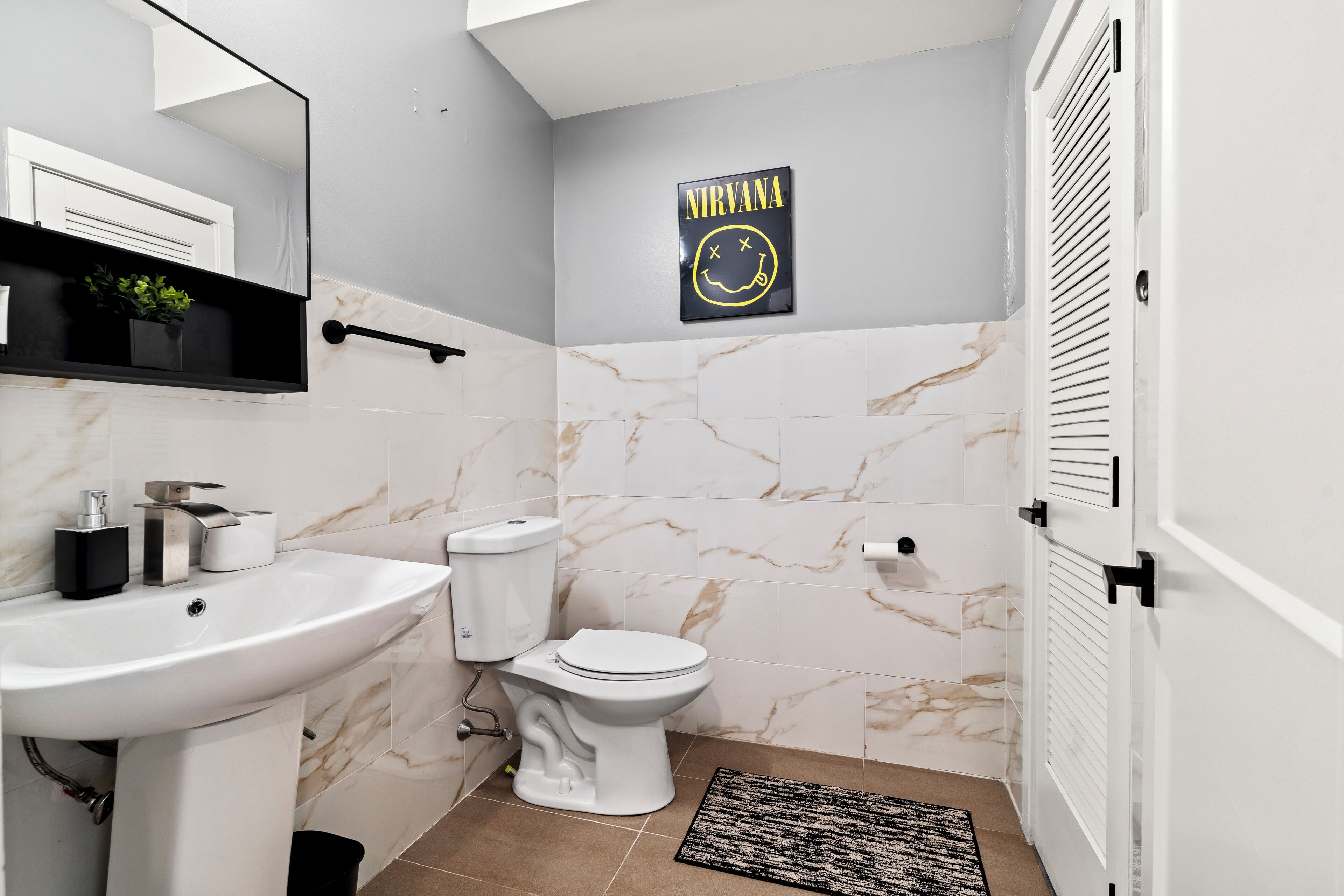 A bathroom with a white sink, toilet, and marble walls.