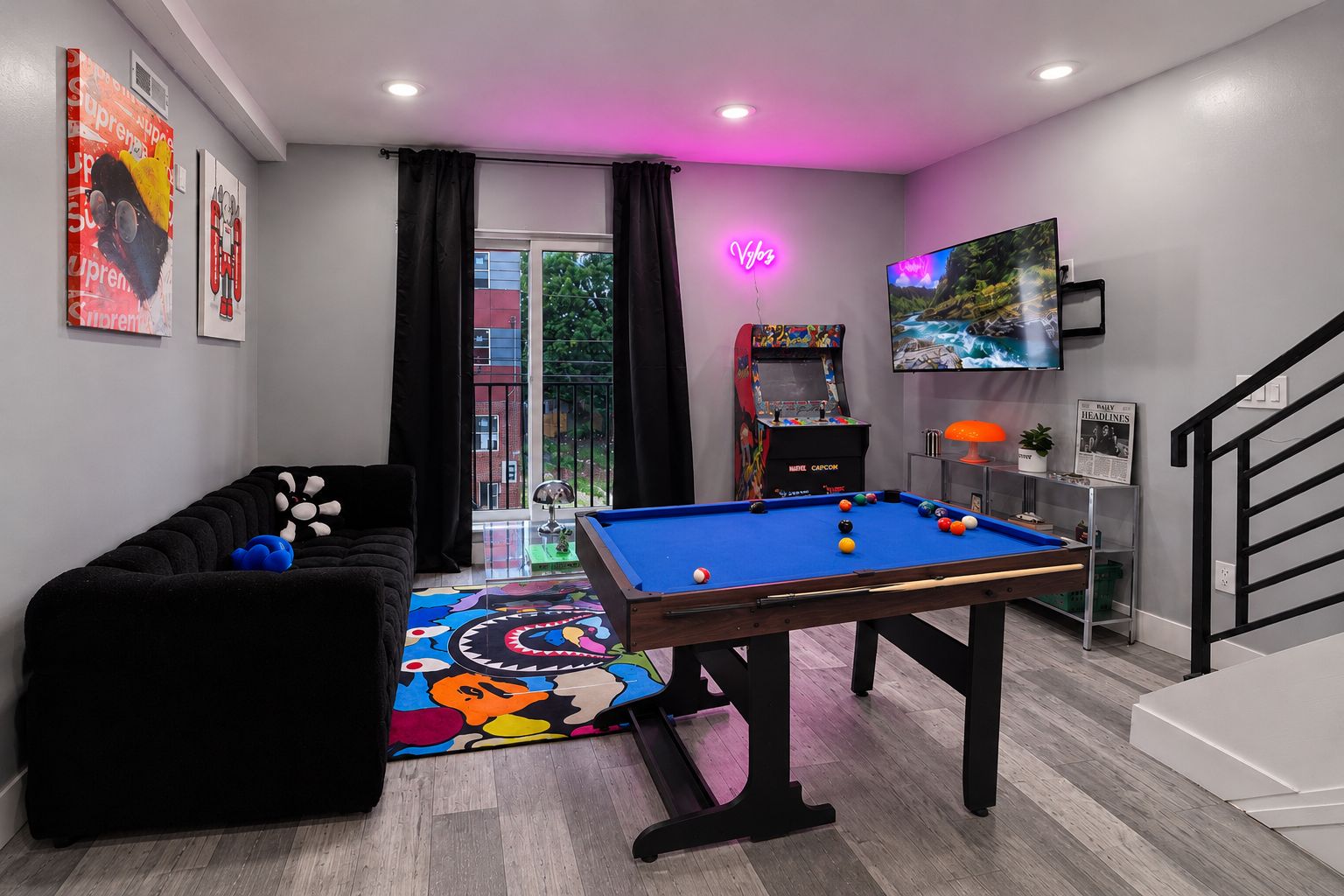 A room with a pool table, a sofa, a neon sign, and a television.