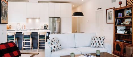A modern living room with a sofa, coffee table, and a bookshelf.