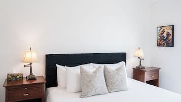 A neatly made bed with white linens, two bedside tables with lamps, and a single wall-mounted artwork.