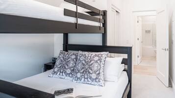 Una cama individual con dos literas, un cabecero oscuro, una mesita de noche con una lámpara y un libro sobre la cama.