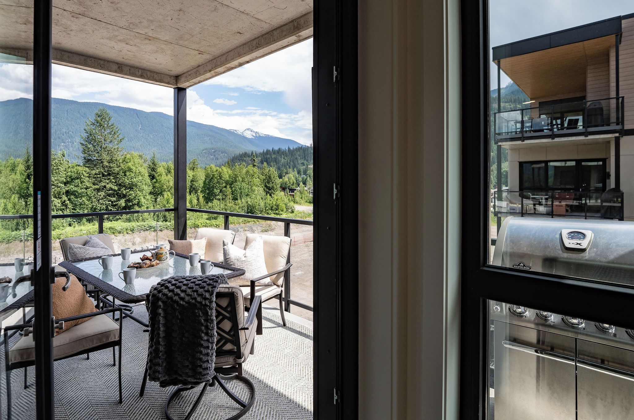 A balcony with a glass table, chairs, and a view of mountains.
