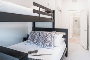 Een stapelbed met een donkere hoofdbord, een nachtkastje met een lamp, en een boek op het bed.