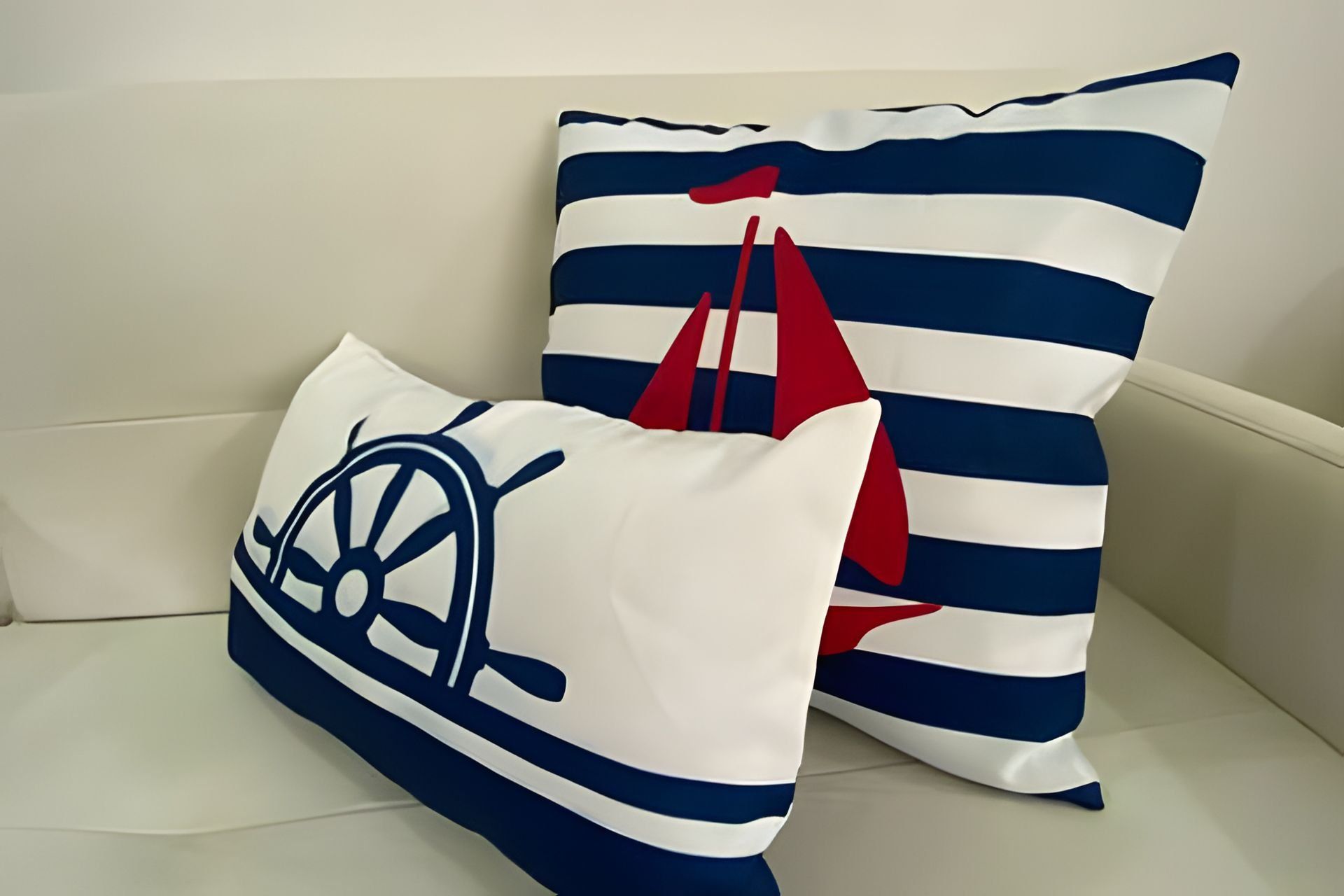Two pillows with nautical designs on a white couch.