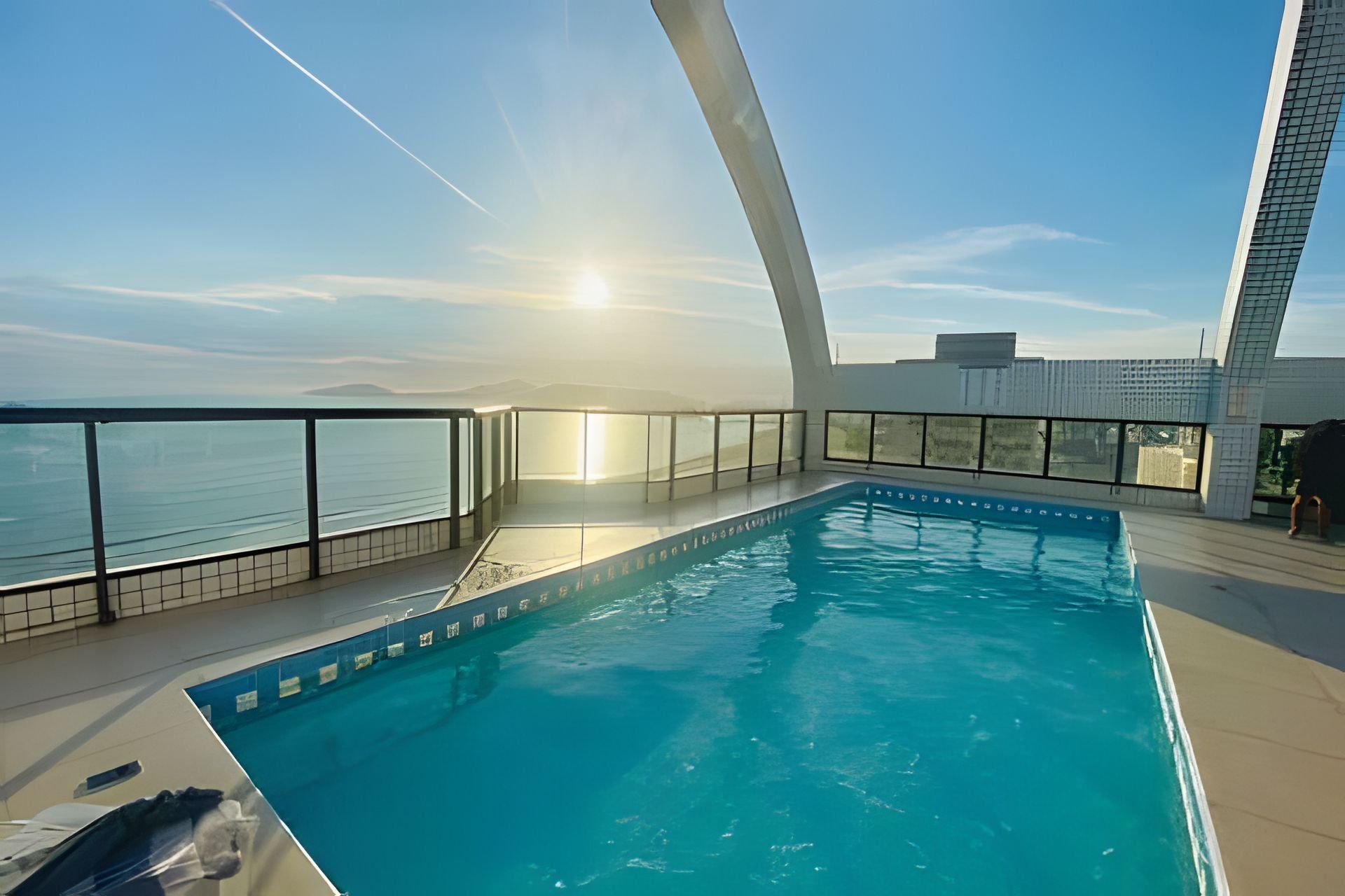 An indoor swimming pool with clear views of the ocean and a modern architectural design.