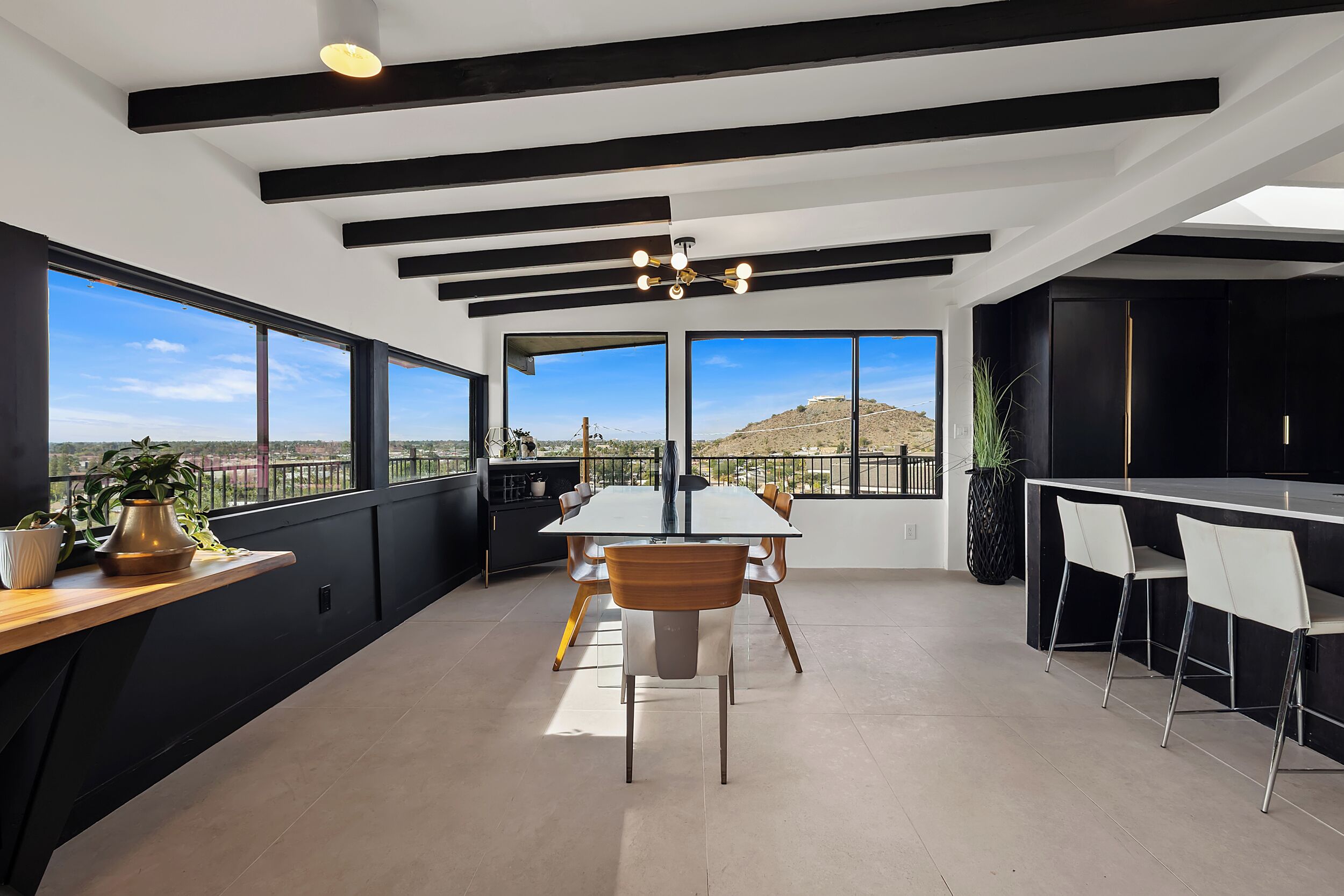 A modern kitchen with a large island, black cabinetry, and a view of the desert.