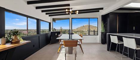 A modern kitchen with a large island, black cabinetry, and a view of the desert.