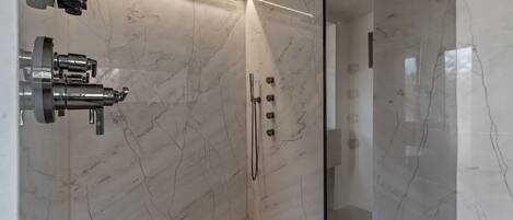 A modern shower with a glass enclosure, marble walls, and a sleek faucet.