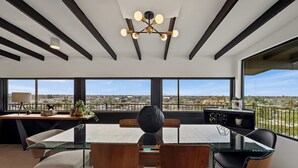A modern dining area with a glass table, wooden chairs, and a city view. - S Haus: Elevated Desert Retreat Breathtaking Views (Phoenix)