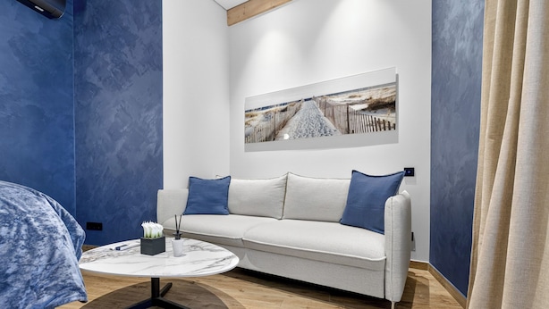 A modern room with a sofa, a round coffee table, and a painting on the wall. - Marmi Boutique Hotel Jurmala (Jūrmala)