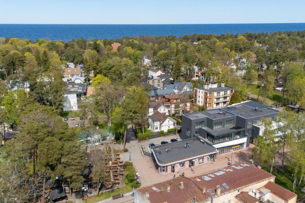 An aerial view of a residential area with houses, a modern building, and a parking lot.