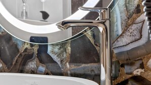 A bathroom with a modern sink, chrome faucet, and a decorative marble backsplash. - Marmi Boutique Hotel Jurmala (Jūrmala)