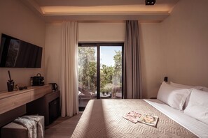 A hotel room with a bed, a desk with a coffee maker, a TV, and a view of the outdoors. - MAHA Her City Living by Semavi (Heraklion)