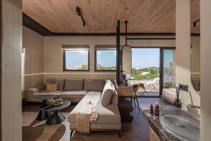 A modern living room with a sofa, coffee table, and a view of the outdoors. - MAHA Her City Living by Semavi (Heraklion)