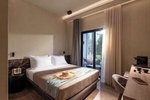 Habitación de hotel con cama, escritorio con cafetera y vista al exterior.