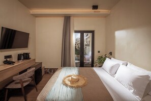 A hotel room with a bed, a desk with a telephone and a coffee maker, a television mounted on the wall, and a view of the outside through a glass door.