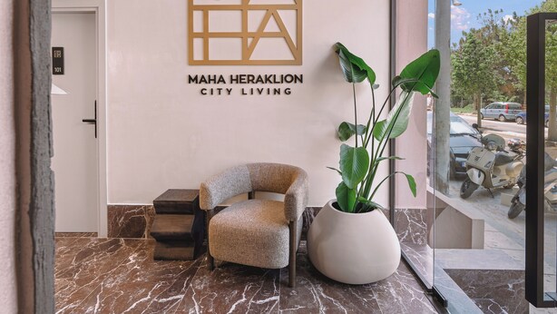 A lobby with a seating area, a large potted plant, and a wall sign for 'MAHA HERAKLION CITY LIVING.' - MAHA Her City Living by Semavi (Heraklion)