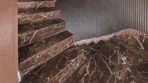 A staircase with marble steps and a textured wall. - MAHA Her City Living by Semavi (Heraklion)